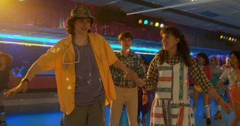 Stranger Things characters, El and Mike skate with bucket hats in a roller rink. Set in the 1980s, ‘80s music, fashion, and other memorabilia make frequent occurrences in the hit Netflix series.