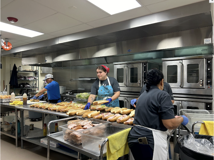 The kitchen staff works quickly in an assembly line to prepare Italian submarine sandwiches before lunch time on October 20.
