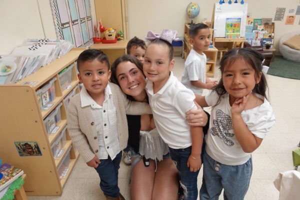Sabrina Feldman ('26) and Head Start preschool students take a minute to smile for a picture during Yoga Day, where they were able to practice animal yoga poses. This activity was made as a result of Chloe Hinder's summer 2024 research on behavior/behavioral development.
