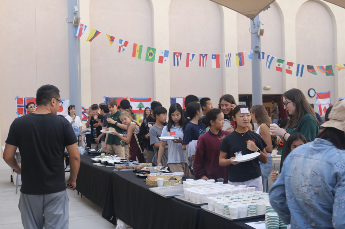 Students lined up for food across three tables on the terrace. The last table was full of desserts like cake, matcha, and gelato. 