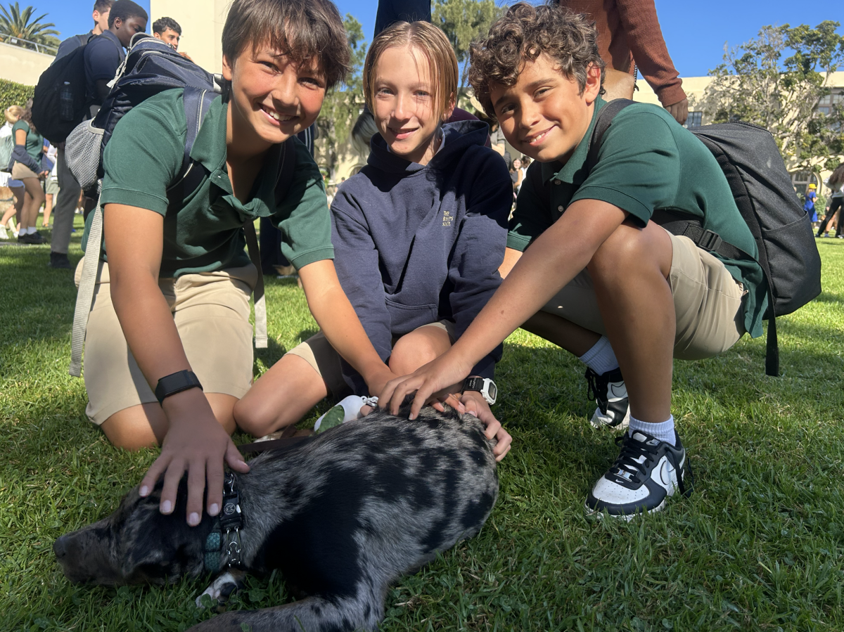 (from left to right) Nathaniel Hendrickson (‘31), Benjamin Hill (‘31), and Cameron Sibley (‘31) are all smiles as they pet Brady, Ben’s spotted dog, who was blessed. “[Brady] was very excited and happy to be there,” he said.