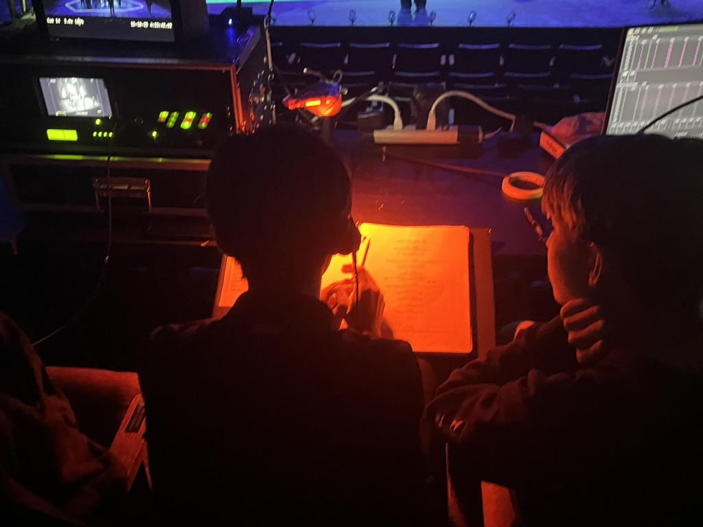 Edward Baek (‘28), the stage manager and Weston Gaylord (‘29), the lighting operator, go over lighting cues during a break in a rehearsal. 