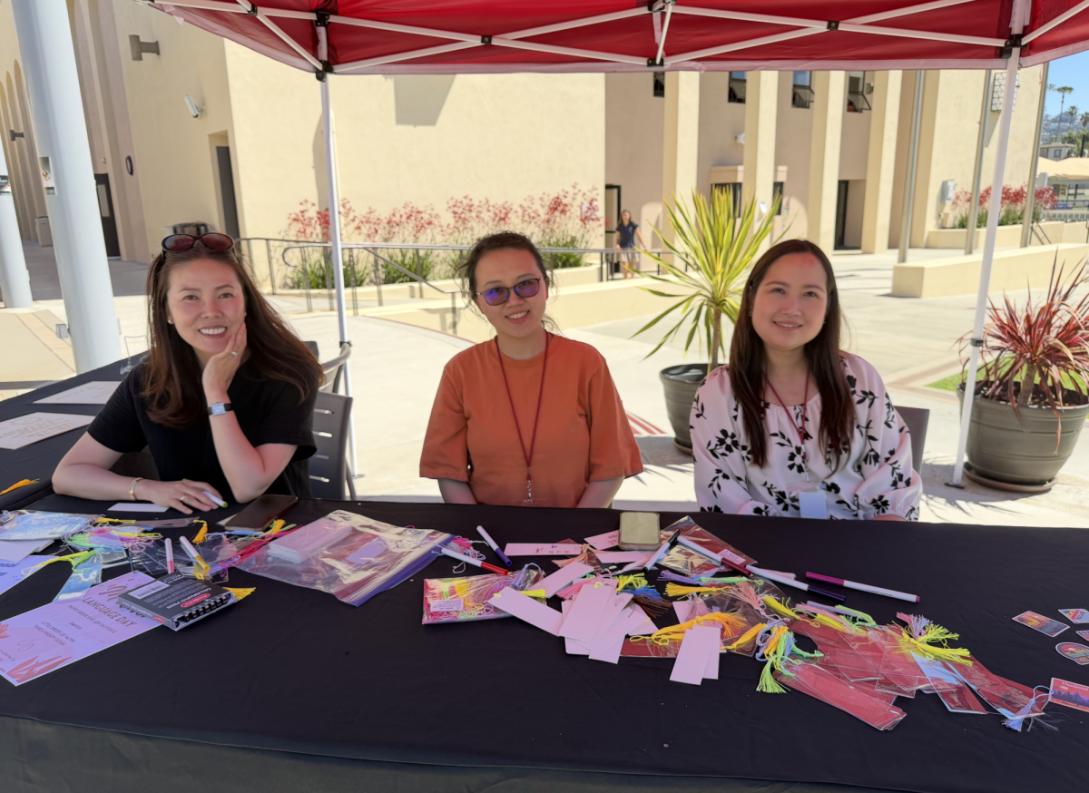 From left to right, Ms. Susan Lee, mother to Elaina Lee (‘29), Ms. Yan Pang, mother to Candice Ding (‘31), and Ms. Sutthisiri Towry, mother to Brianna Towry (‘30), sit at the bookmark-making booth. “Language is such an important part of the culture that, even if it's just a little bit of exposure like learning how to write your name in a foreign language,” said Ms. Lee.
